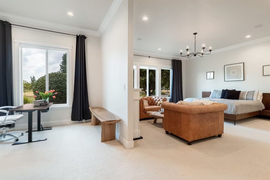 Primary suite with a sitting area, desk nook and windows to the grounds